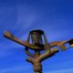 "Close-up of a rusted metal sprinkler head against a clear blue sky, used in agricultural or lawn irrigation systems.
