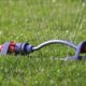 Close-up of a lawn sprinkler spraying water in even streams over green grass, showing effective residential irrigation in action.